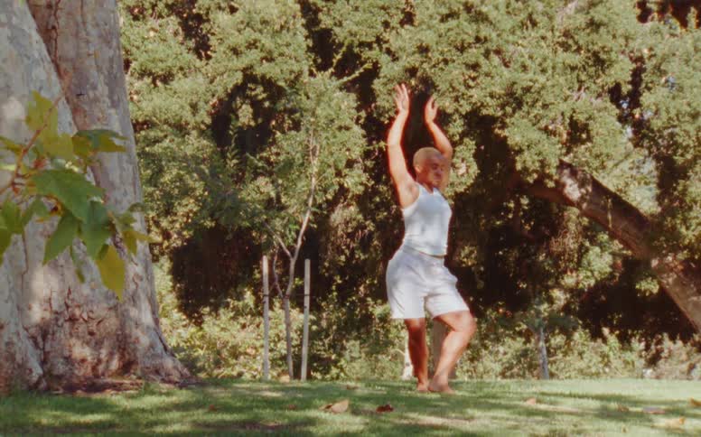 Woman dances on grass near base of cliff