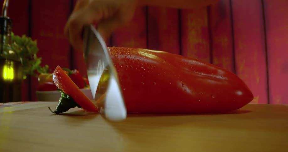 Knife slices pepper on cutting board