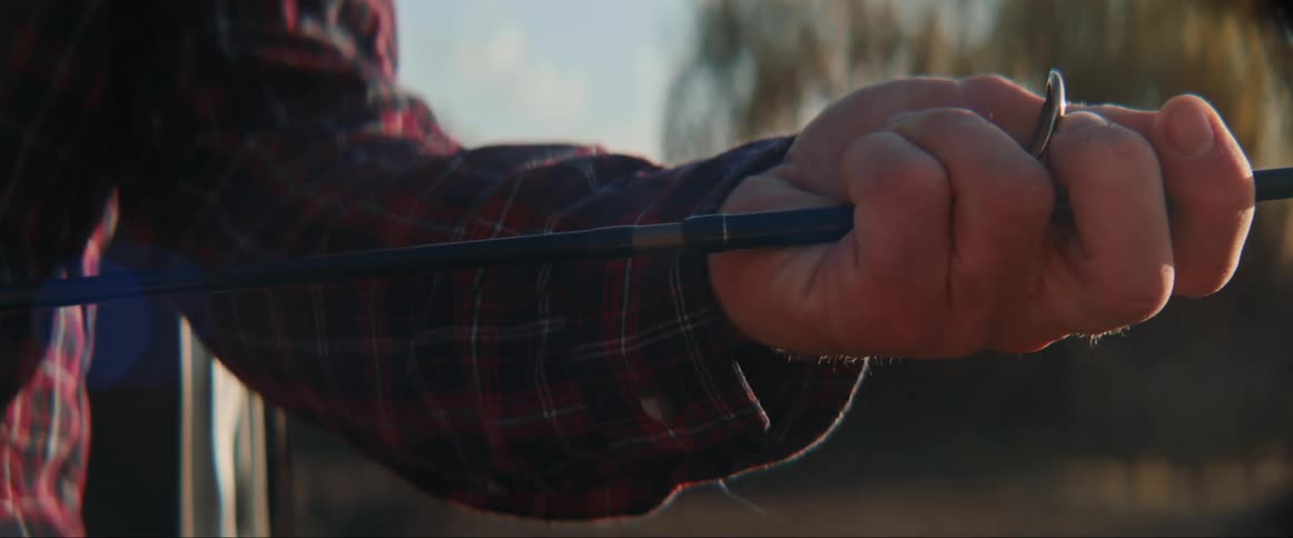 Man with plaid shirt attaches fishing poles