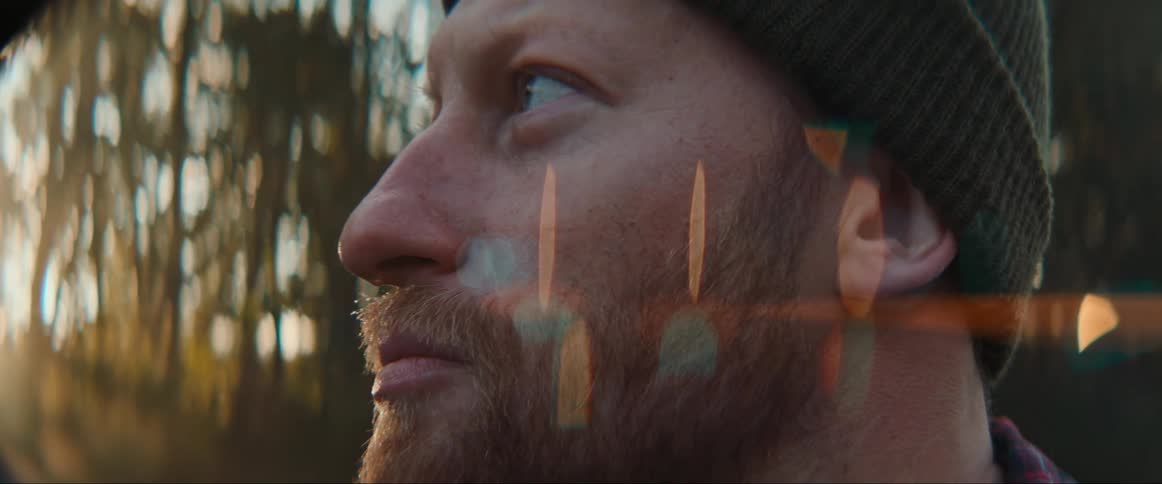 A mans head is shown against some vines in the background as he looks around in awe