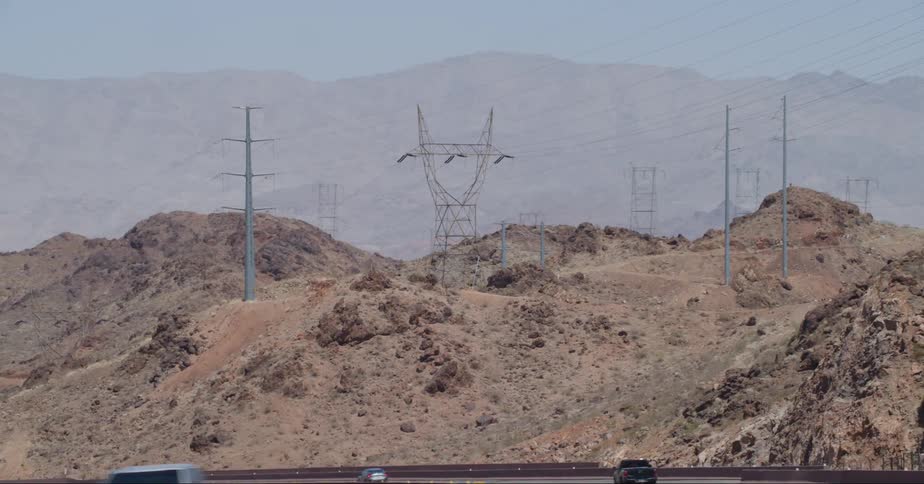 View of electricity transmission towers on natural cliffs next to a road