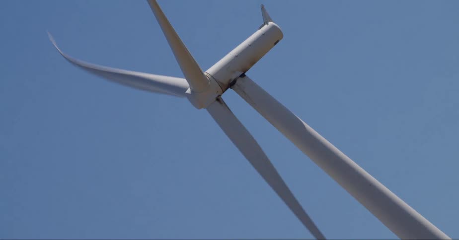 Close up view of a wind turbine as it spins under a clear blue sky