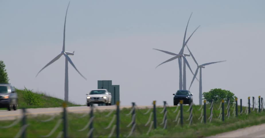 Vehicles drive on road in front of wind turbines