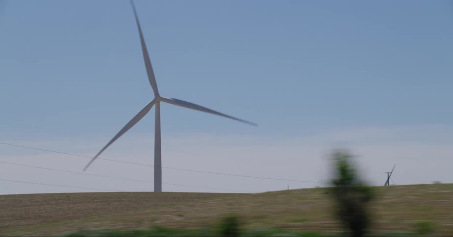 Wind turbines spin near utility wires in a rural area