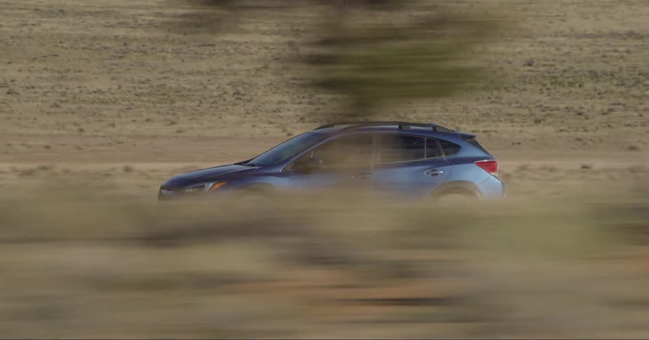 A person driving a blue car in the desert landscape