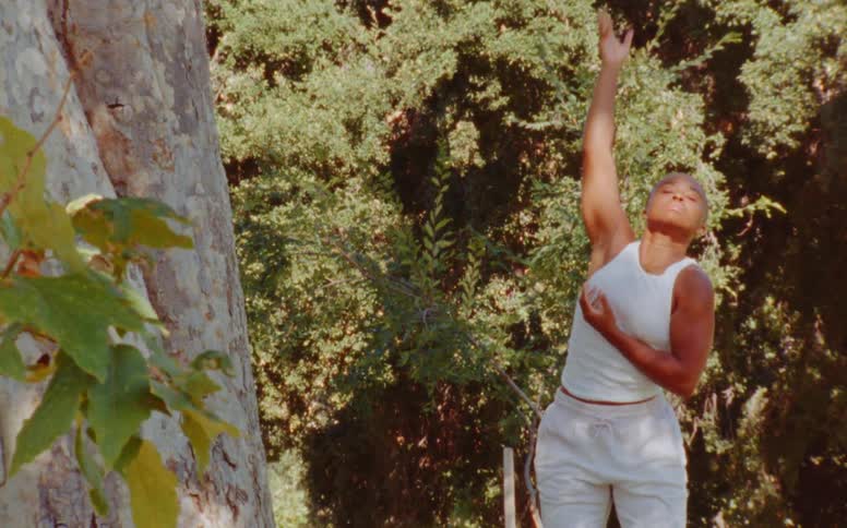Woman dances outdoors near woods