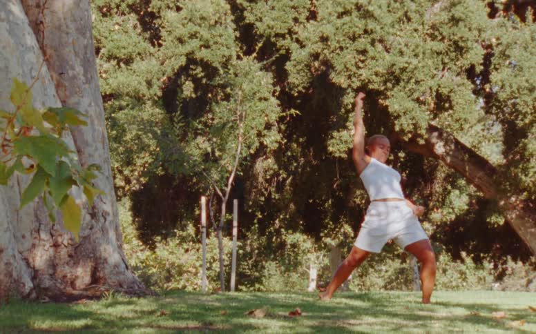 A young girl dancing outdoors in a park