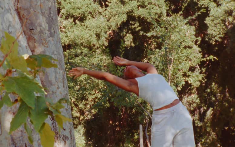 Woman dances outdoors near tree