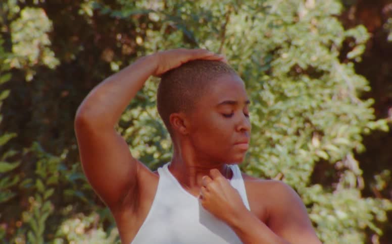 Person stands near tree caressing their head and face