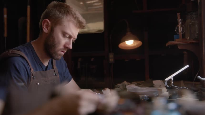 Man works on a delicate piece on his workshop at home