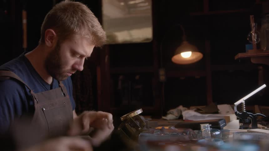 Man in working with a magnifier in an indoor workshop