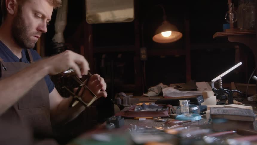 Man picking up a magnifying glass from the tool table