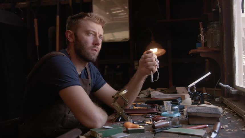 A man sitting at a table full of tools