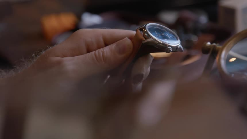 Mans hand holding leather watch strap light brown
