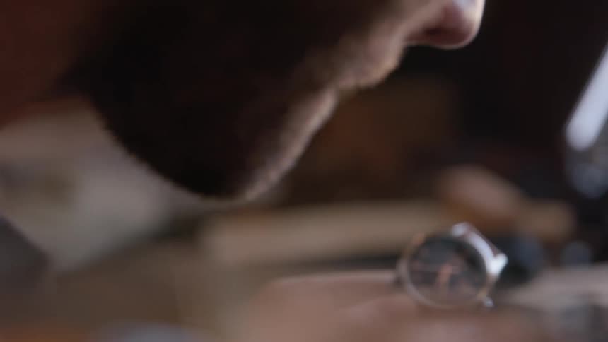 Man with a beard holds a watch with a light brown leather strap