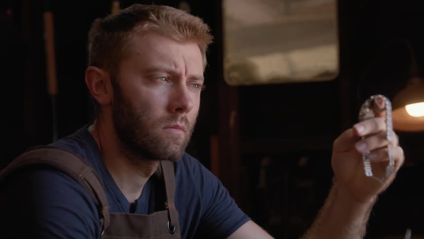 A man working on a silver watch in his workshop