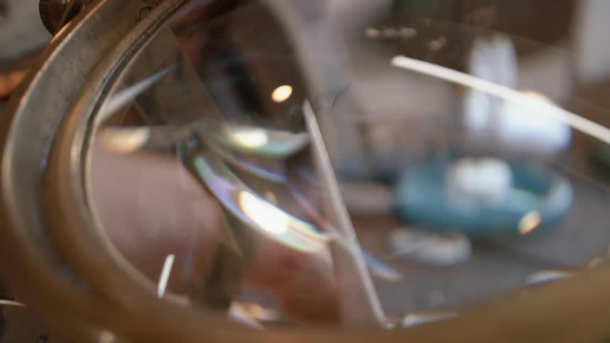 A person puts a tiny watch piece under the magnifying glass