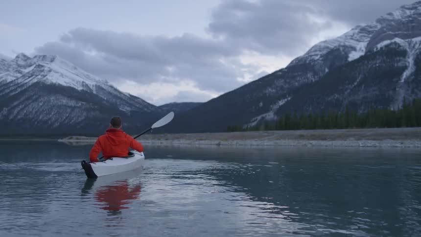 A man is rowing in a lake in a canoe