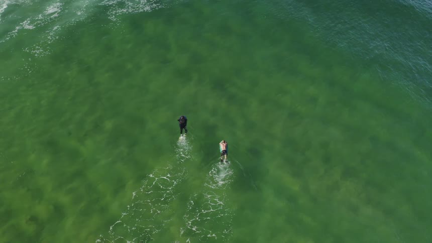 Two people float and kick in the middle of the ocean