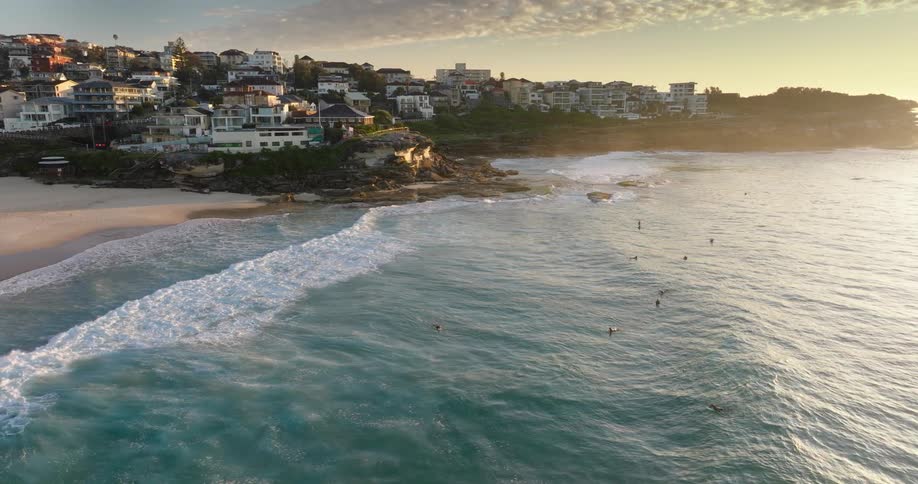 An aerial view of a beach by the sea in an urban city at dawn