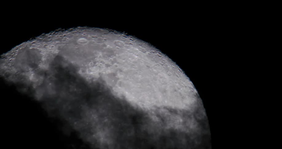Dark clouds move across night sky revealing lunar surface