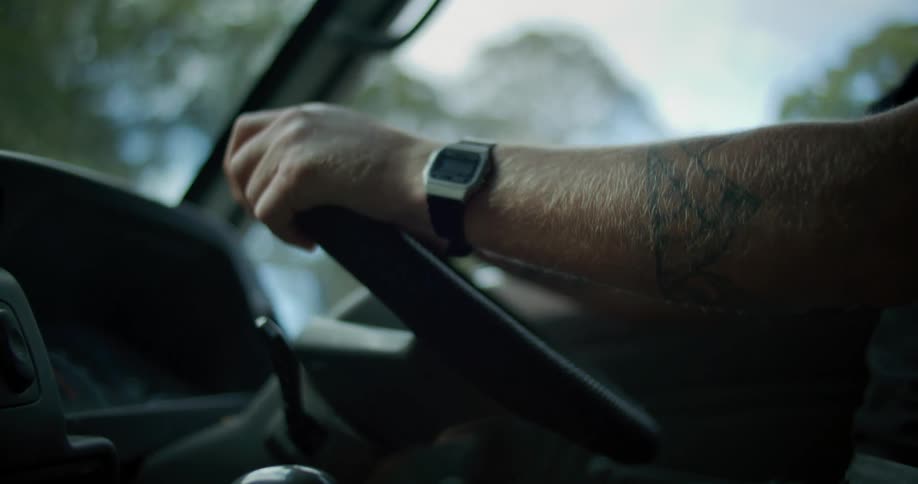 A person with a tattoo on their arm is driving