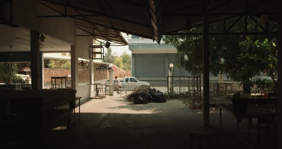 Cyclist pedals along street past pavilion with tables