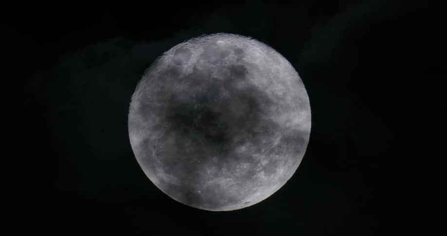 Dark clouds crossing the full moon obscure it