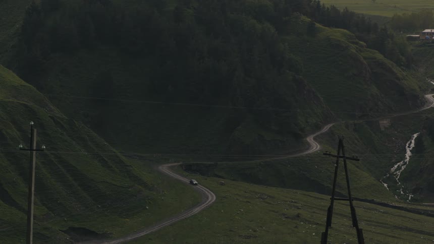 A car driving on the road with green mountains