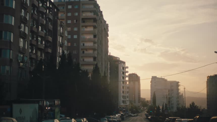 A neighborhood in a city with some tall buildings and several cars parked on the corners of the streets