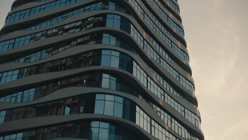 A high rise building has a curving facade and windows on its exterior