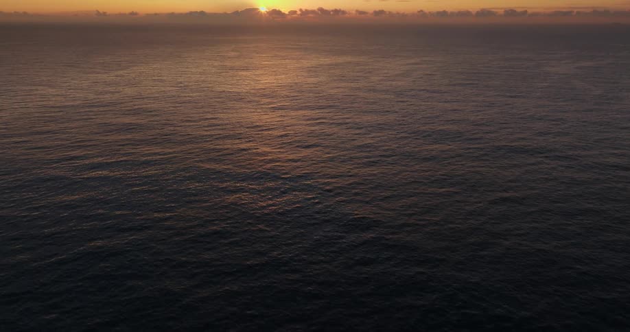 A view of the ocean with the sun rising on the horizon
