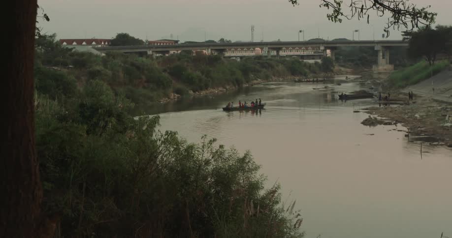 People ride in boat on river toward dock a short distance from bridge
