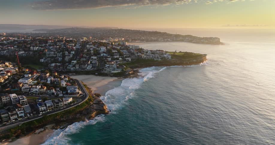 Waves roll onto beach near residential neighborhoods at dawn