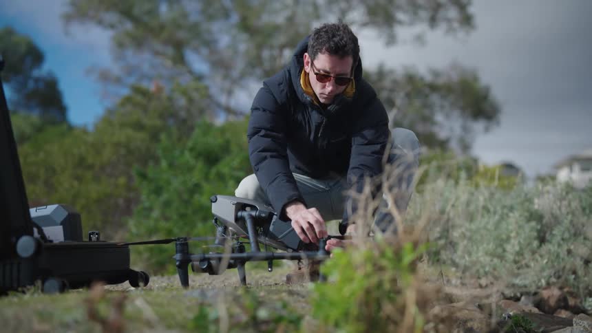 A man squat to assemble a drone at midday