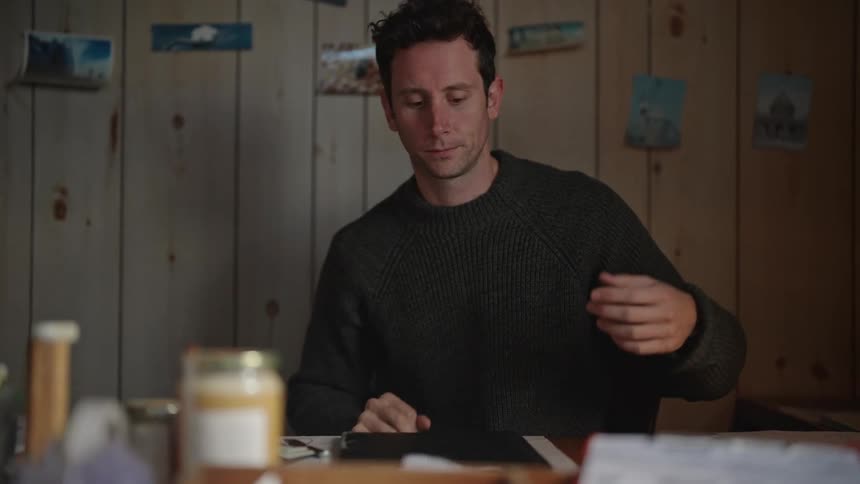 A distressed man sitting closing a book and placing his hands on his face