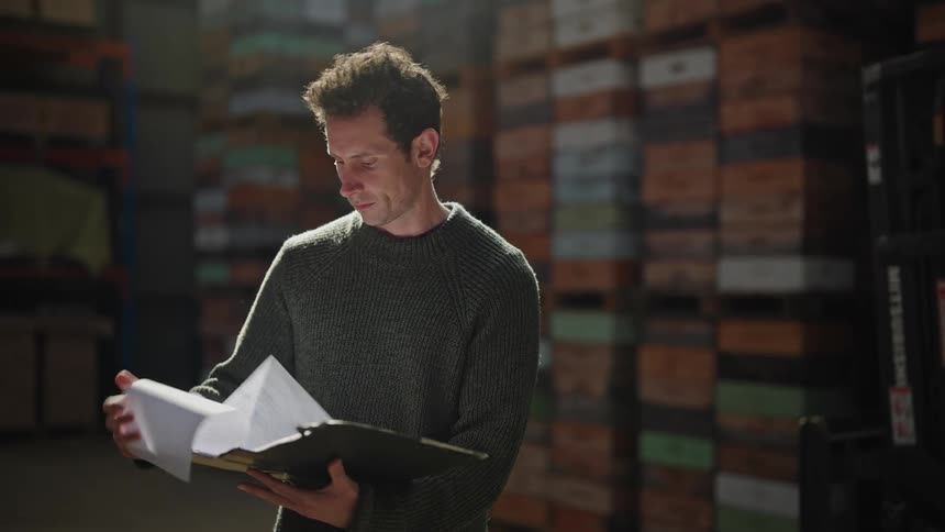 A man with a briefcase reading files and observing containers in the surroundings