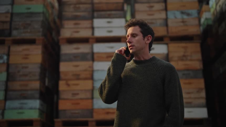 Man talks on phone standing in warehouse