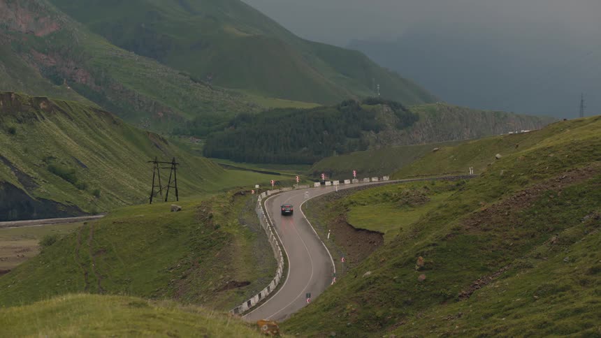 A car driving on a winding road in a natural environment with mountains