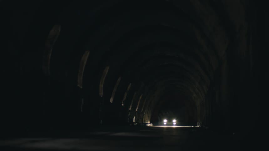 Car driving through a dark and dirty tunnel