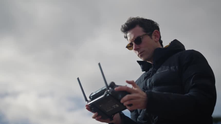 A man wearing sunglasses uses an electronic device