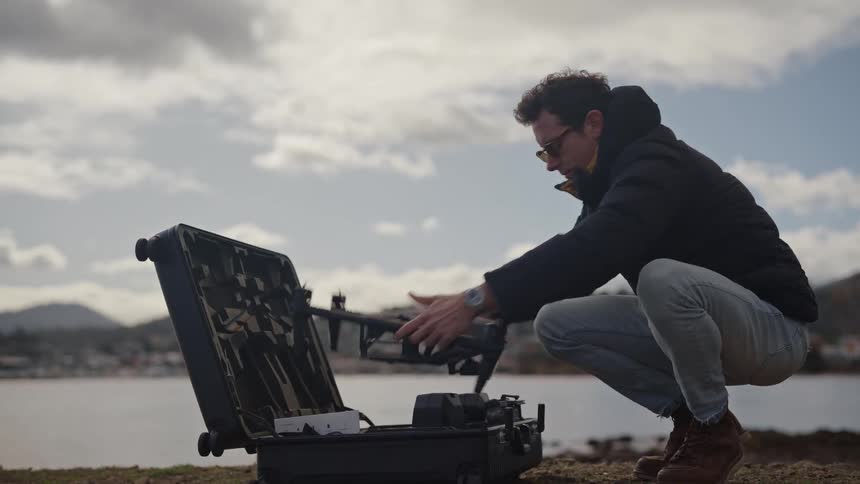 A man takes a drone out of his black suitcase