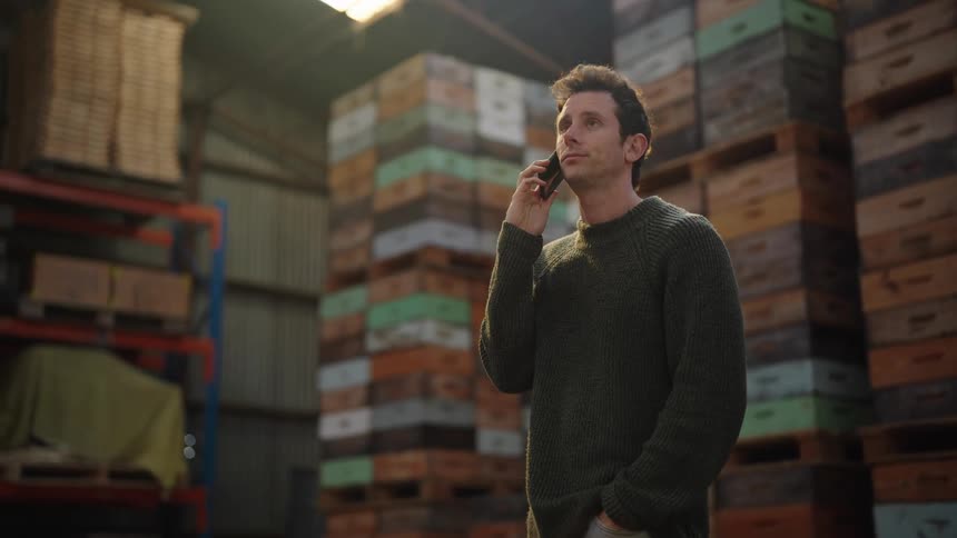 A man is talking on his cell phone inside a warehouse