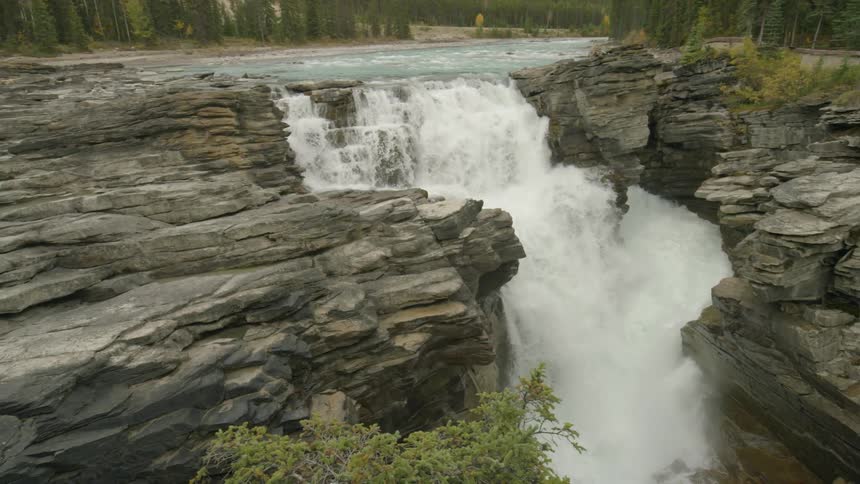 The water from a stream falls off the side of a cliff into a waterfall