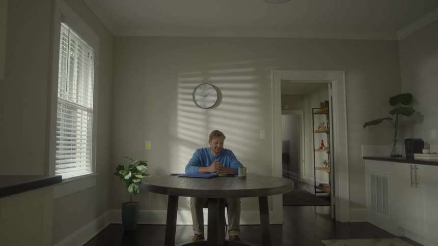 An adult man sitting on a chair with arms and laptop resting on the table