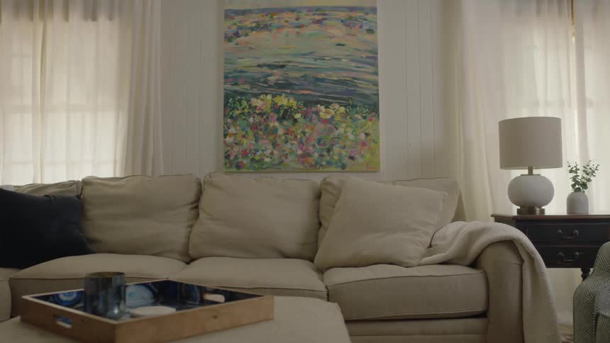 A woman happily using her phone stands up from the sofa in a living room