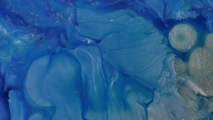 A blue liquid with some bubbles is expanding in an environment