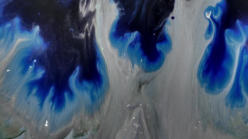 A blue and black liquid paint is dripping into a gray liquid and taking over it
