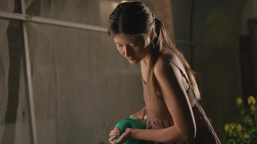 A woman is watering a plantin a interior garden using water from a hose