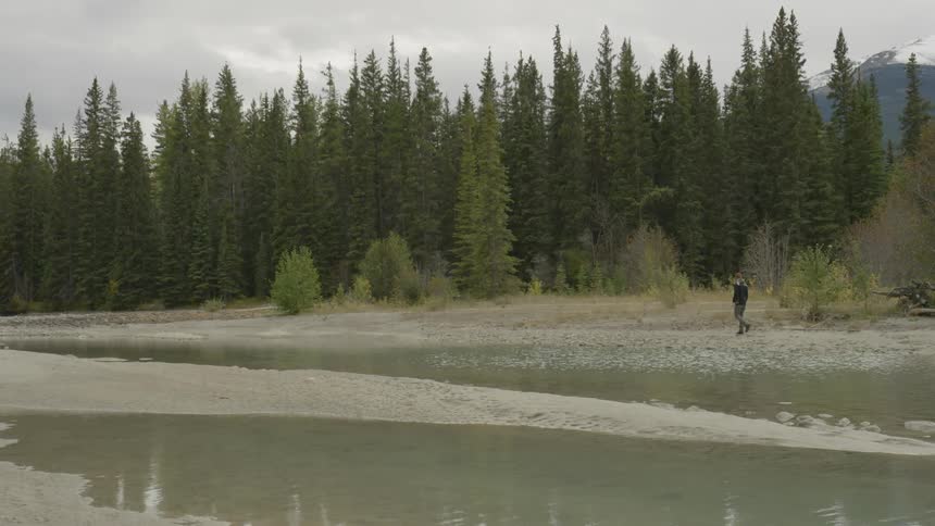 A man is hiking along the water ahead